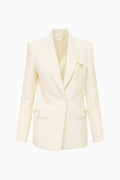 Cream wool-blend blazer with satin bow trim on flap pockets and sleeves, flat lay