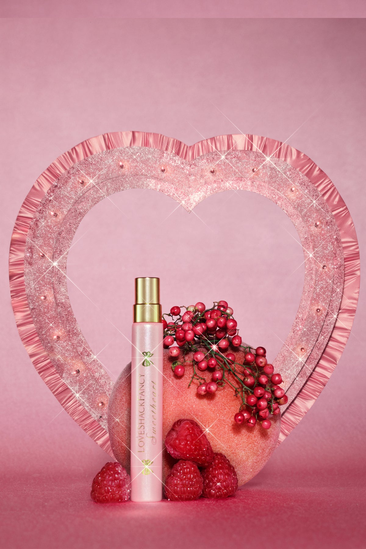 Pink perfume travel spray bottle and small bottles on glittery heart display.