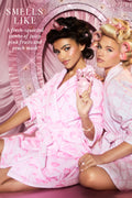 Pink perfume travel spray bottle held by model in ruffled pink outfit.