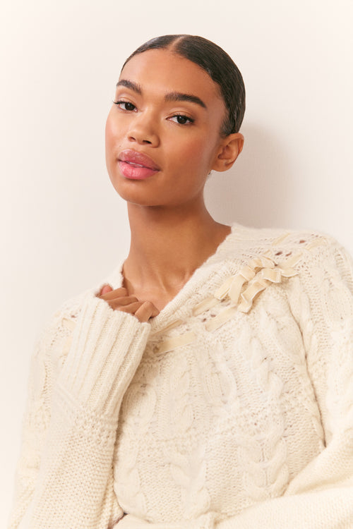 Ivory knit cotton pullover with ruffled ribbon neckline and cable-knit sleeves