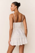 White cotton mini dress with spaghetti straps, lace trim, and subtle bow motif pattern