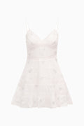 White cotton mini dress with thin spaghetti straps and tiered skirt, all-over bow motifs