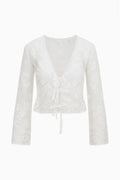 White sheer lace top with V-neck, ruffled trim, long sleeves, center tie tassel