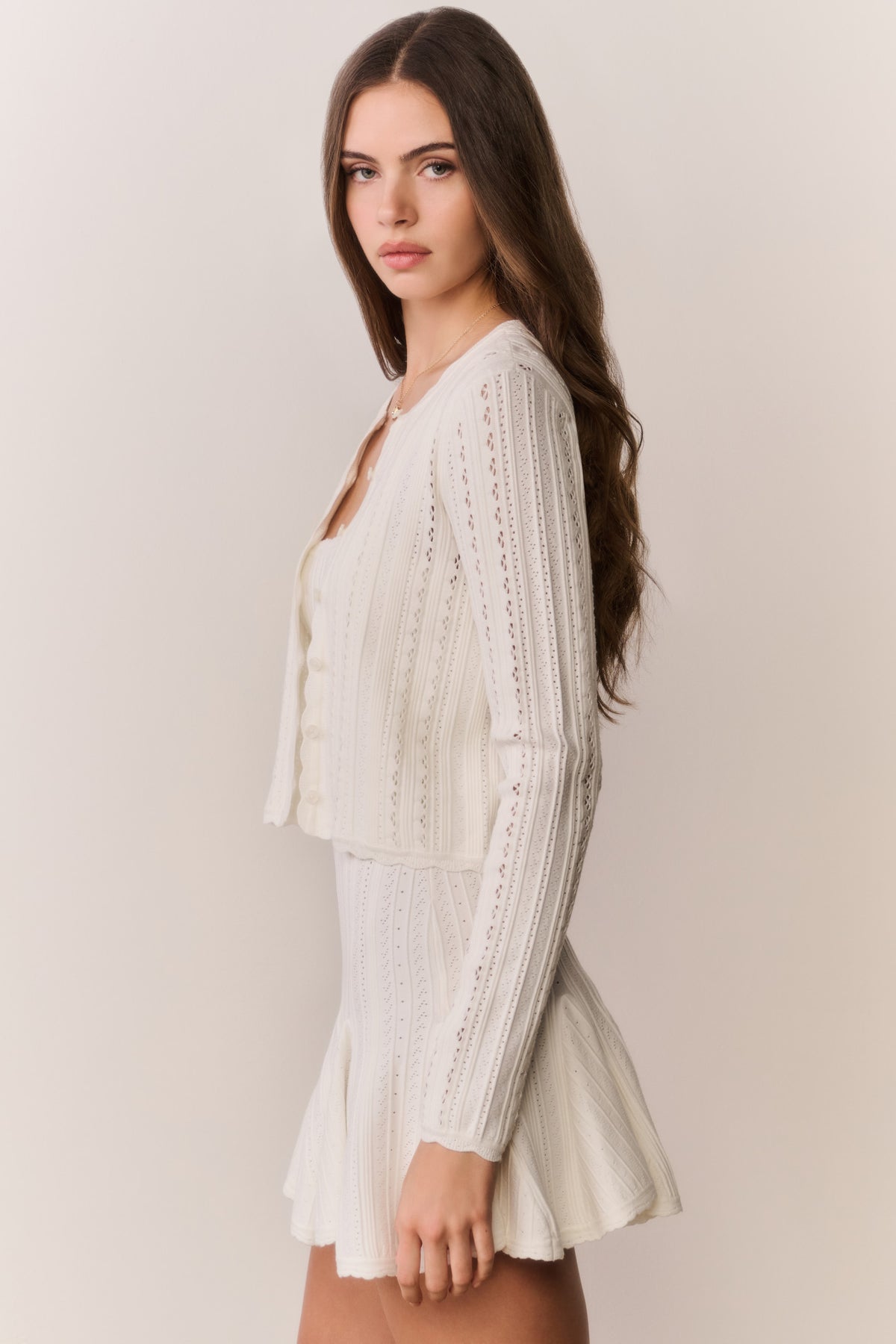 White pointelle stretch cardigan with open front and long sleeves, textured knit