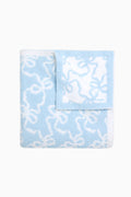 Light blue teddy bow blanket, folded with white bow-pattern design on plush fabric