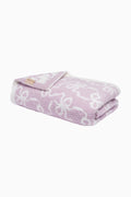 Light purple teddy bow blanket, folded with white pattern and small fabric tag