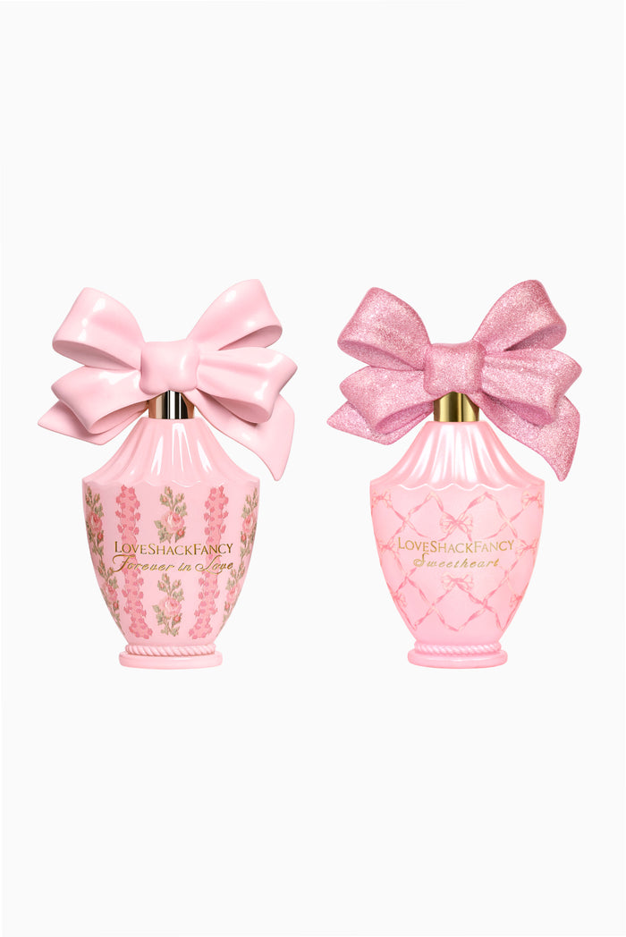 Two pink perfume bottles with satin bows and decorative gold caps, on white