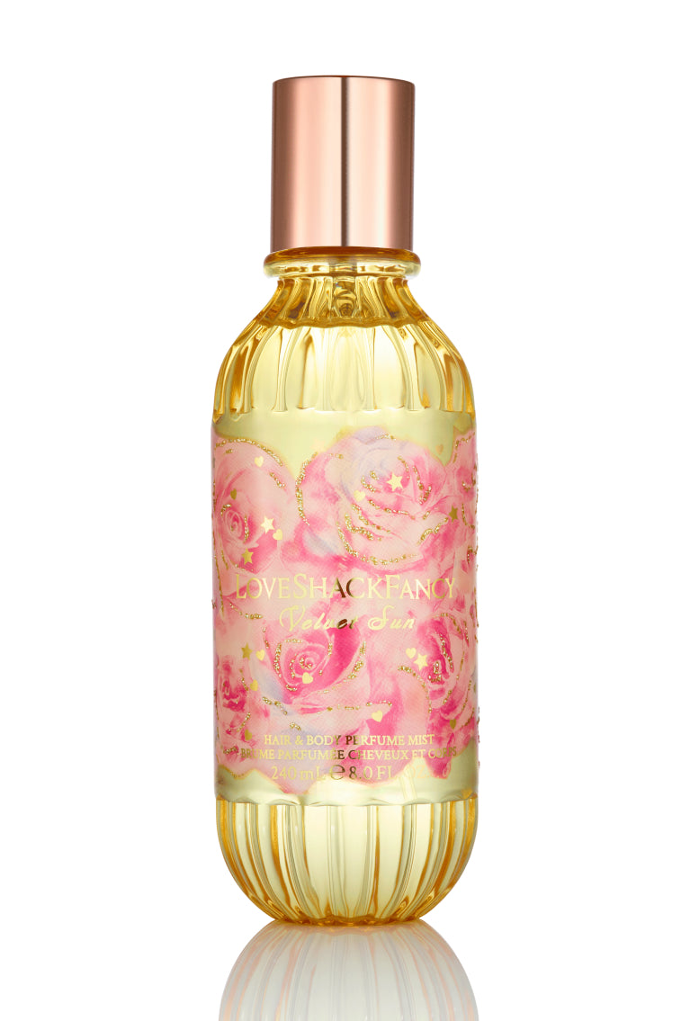 Hair and body perfume mist bottle with gold liquid, metallic cap, and floral label