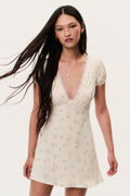 Floral mini dress with lace V-neck and short puff sleeves, light cream background