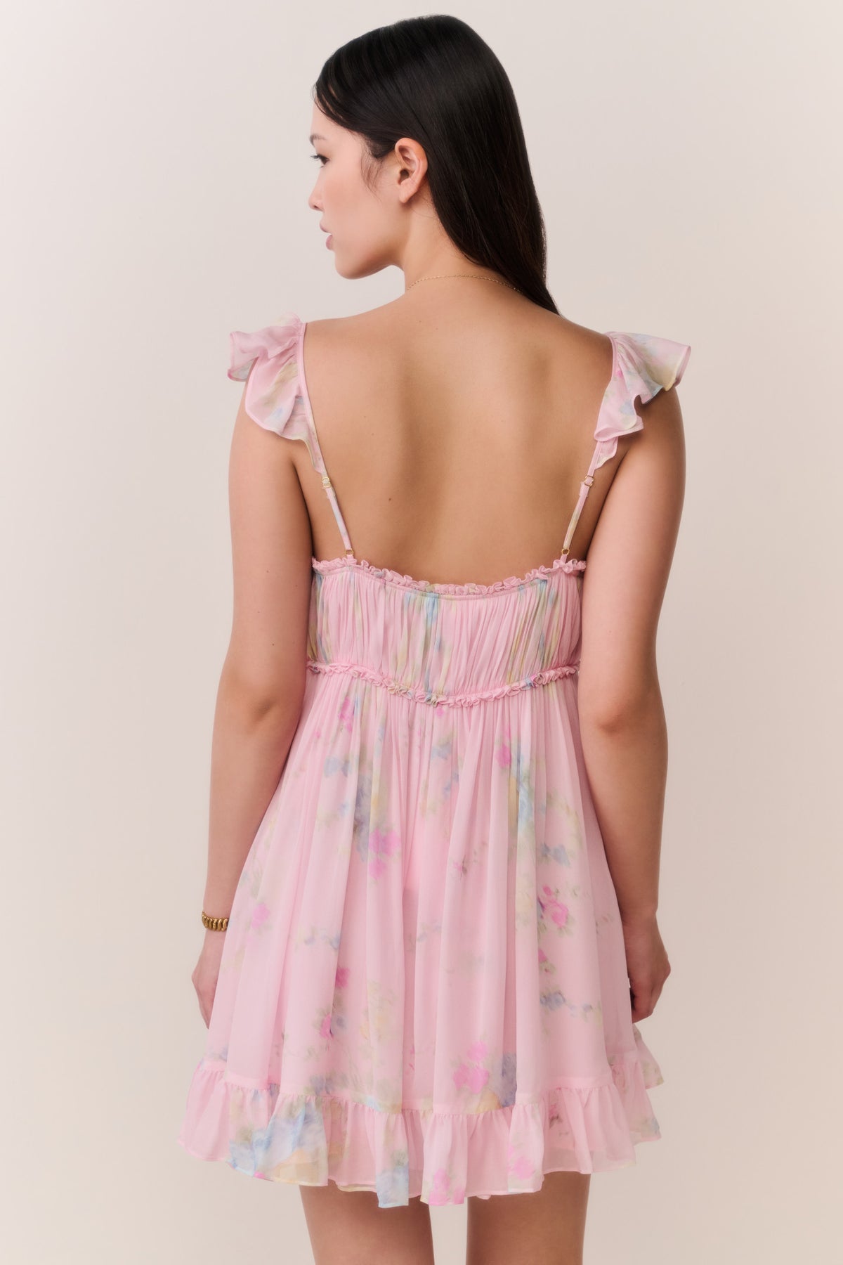 Pink floral chiffon mini dress with open back straps, ruched bodice, and ruffled hem