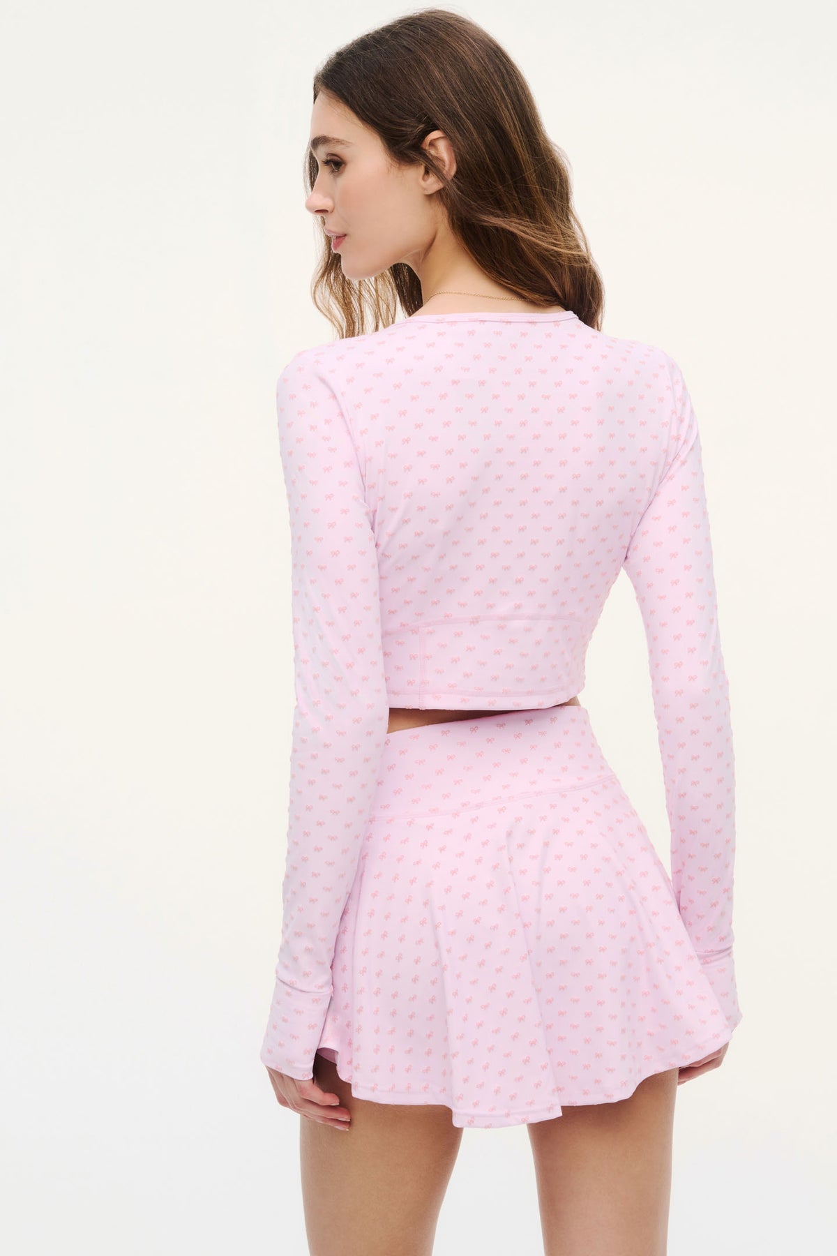 Back view of cropped zip jacket with allover bow print, long sleeves