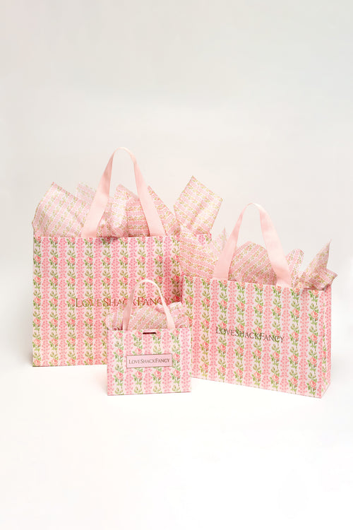 Pink patterned gift bags set with ribbon handles and a small matching tote