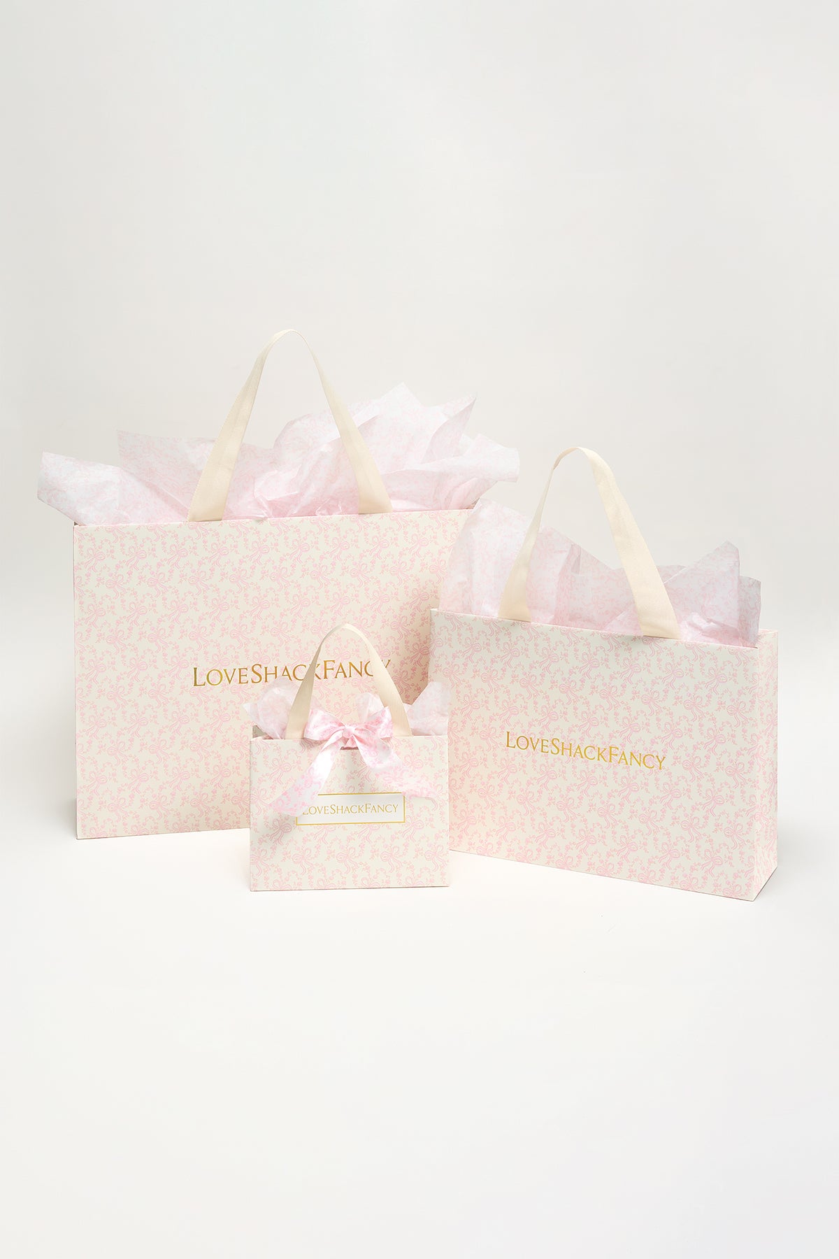 Pink patterned gift bags set with ribbon handles, featuring a bow accent