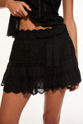 Black lace mini skirt close-up with ruffle tiers and bow at waist