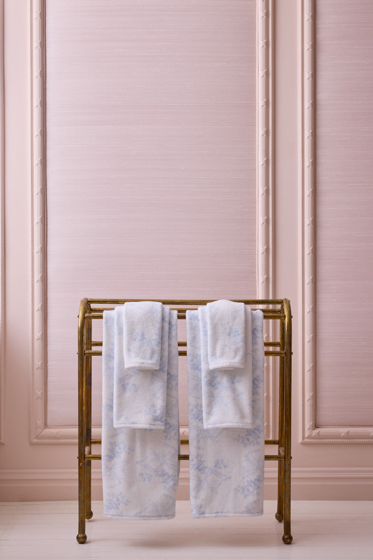 Light blue cotton wash cloths folded on a gold rack