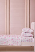 Pink floral sheet set with two folded pillow shams on a bed