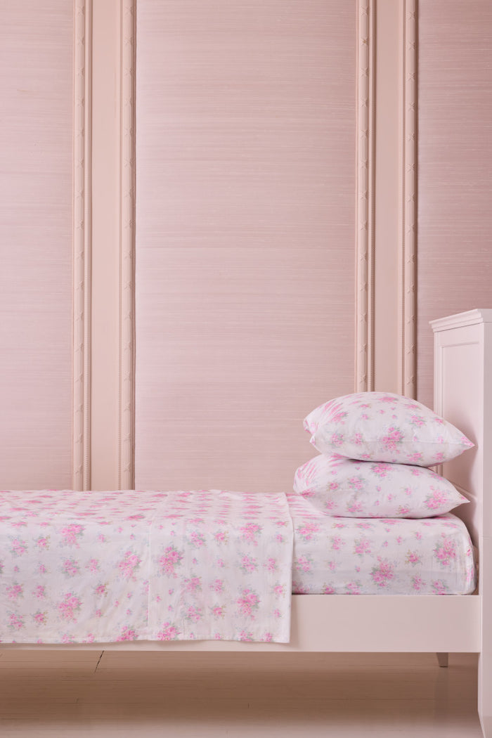 Pink floral sheet set with two folded pillow shams on a bed