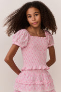 Pink lattice print top with puff sleeves and ruffled layers at hem, front close-up
