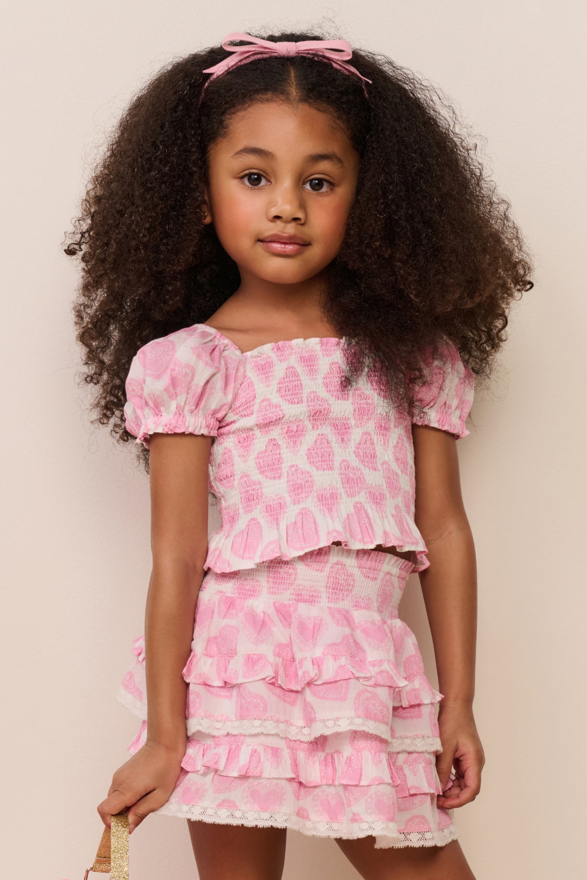 Girls pink heart-print top close-up with puff sleeves and layered ruffle peplum
