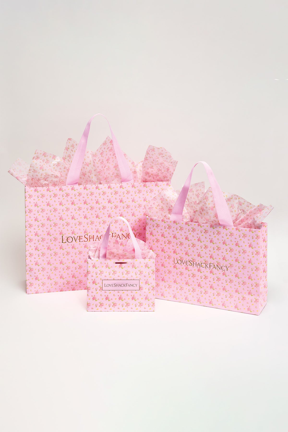 Pink patterned gift bags set with ribbon handles and a bow-topped bag