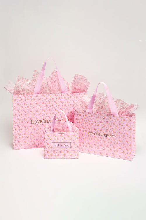 Pink patterned gift bags set with ribbon handles and a bow-topped bag