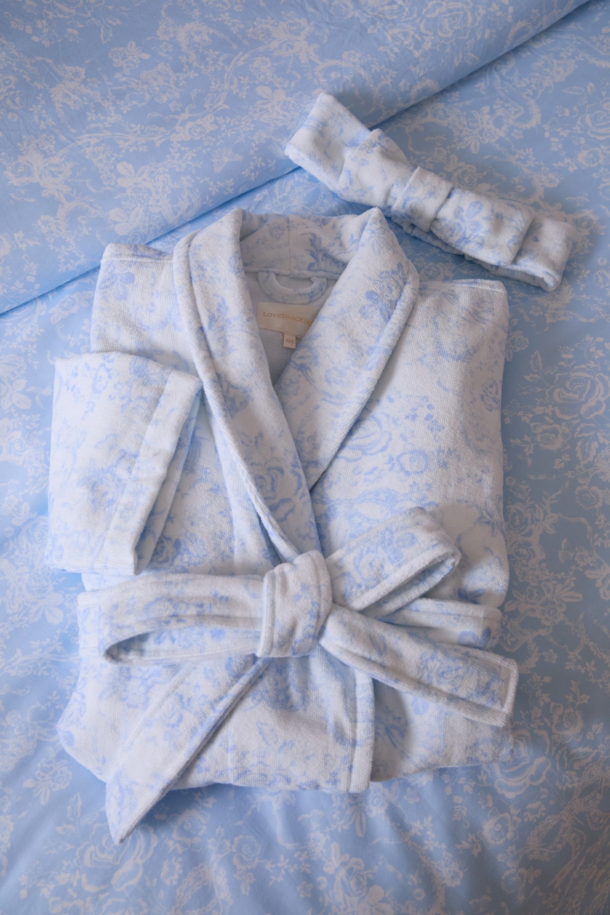 Light blue floral cotton bathrobe detail: tied belt at waist and shawl collar