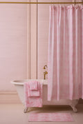 Cotton hand towel in light pink, folded and placed near a matching rug