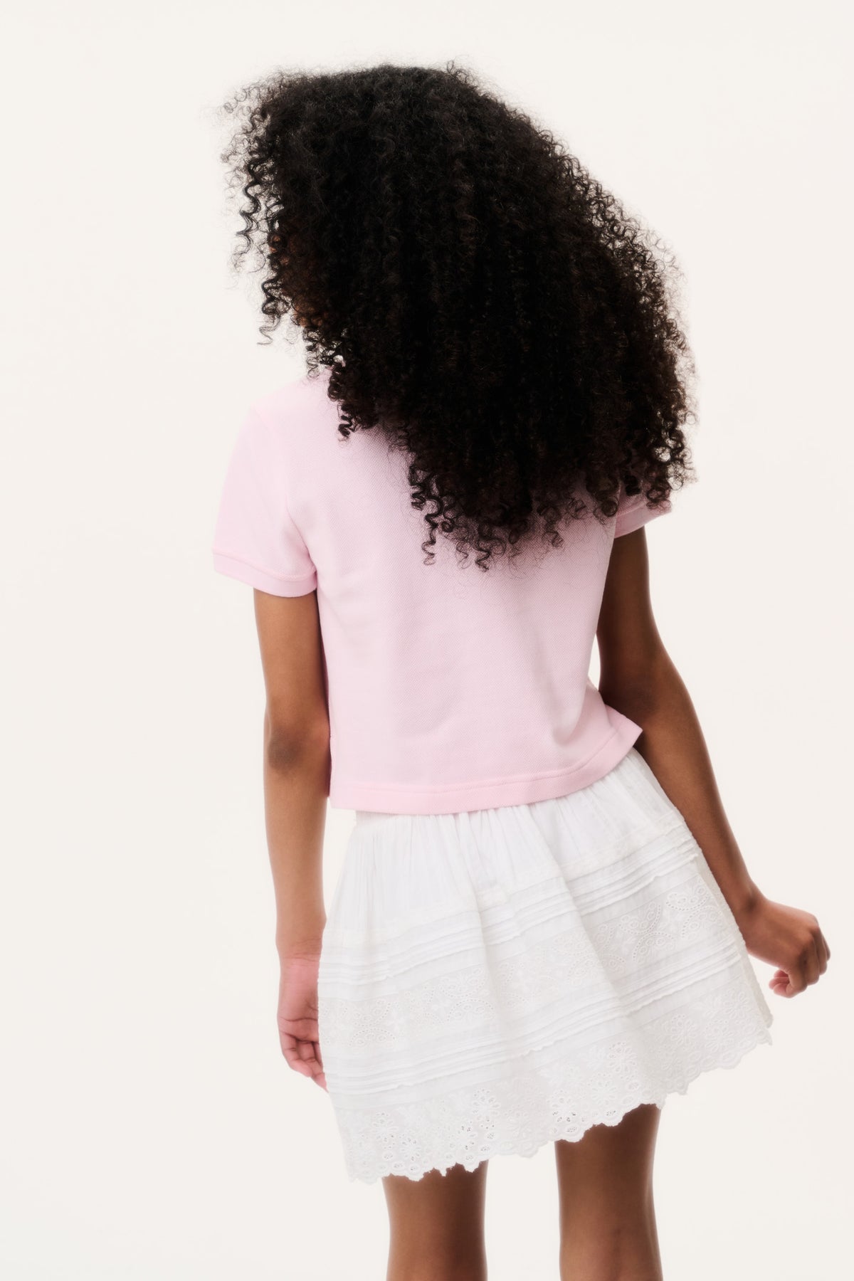 Light pink polo shirt back view with short sleeves, paired with white tiered skirt