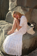 White maxi dress with lace trim, V-neck button front, and tiered hem