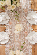 White lace table runner with vertical embroidered motifs and floral trim