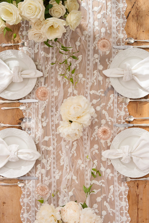 White lace table runner with vertical embroidered motifs and floral trim