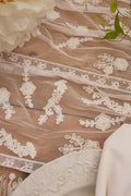 White lace table runner close-up with scalloped edge and floral appliques