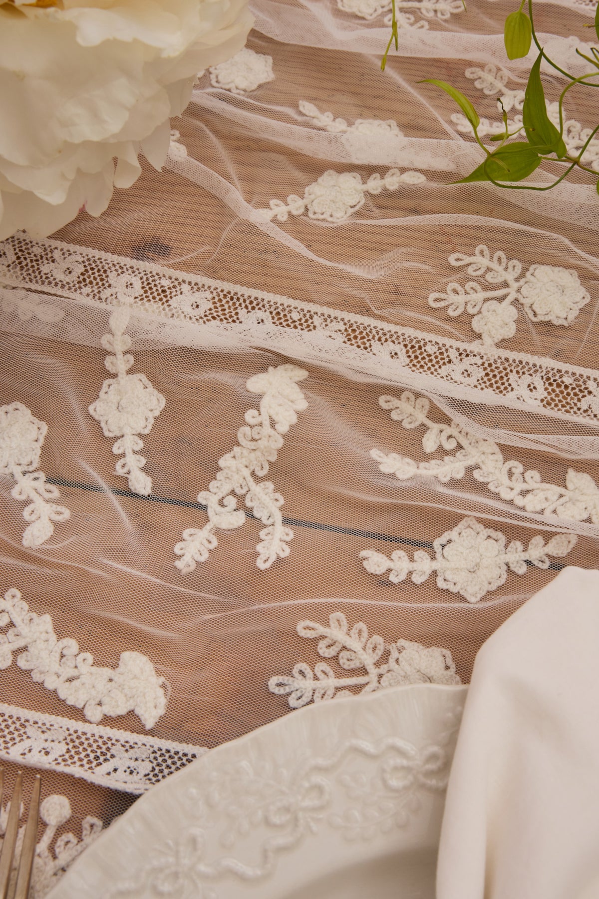 White lace table runner close-up with scalloped edge and floral appliques