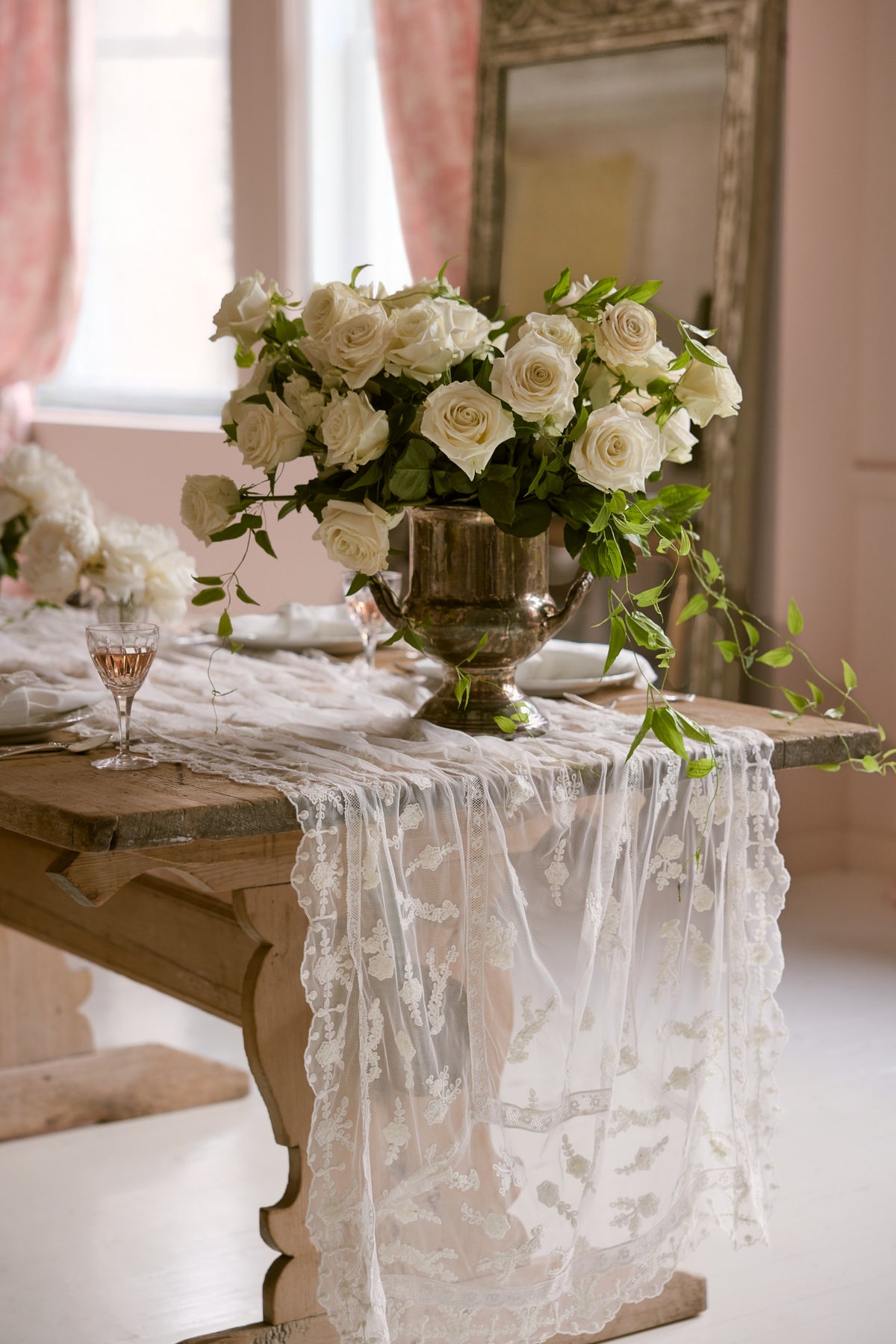 White lace table runner draped on dining table with floral centerpiece