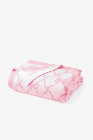 Pink bow-pattern throw blanket, neatly folded and rolled