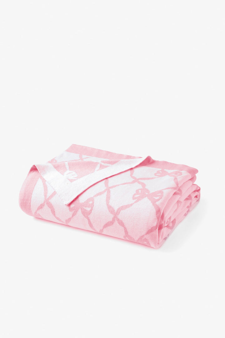 Pink bow-pattern throw blanket, neatly folded and rolled