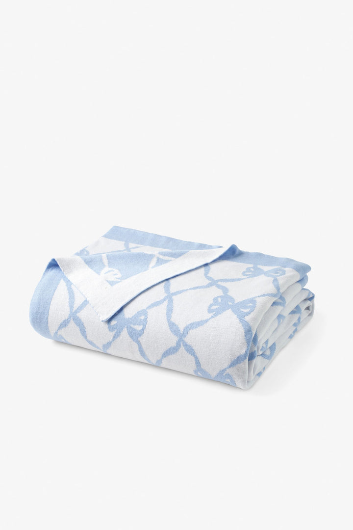 Blue bow-pattern throw blanket, folded roll with bow lattice pattern